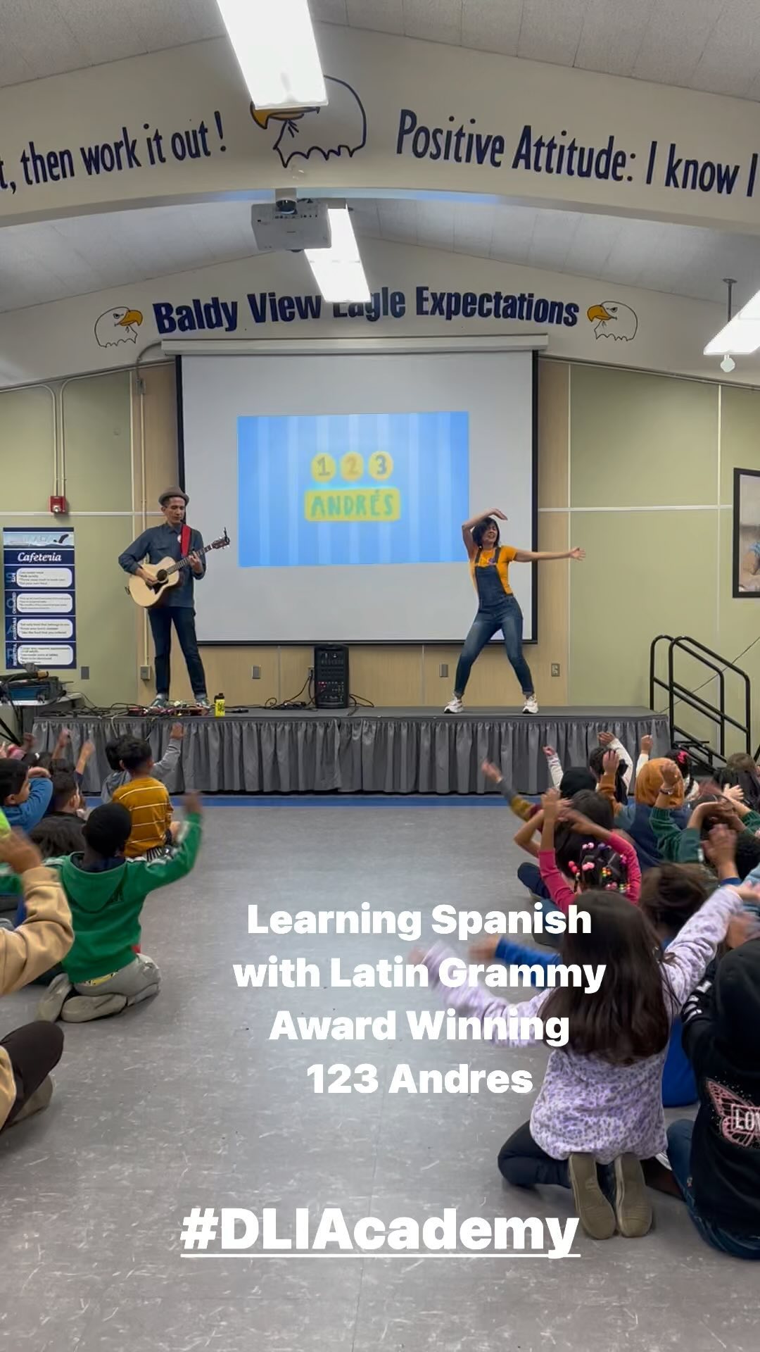 Baldy View students raising their hands while 123 Andrés performs beneath the Baldy View Eagle Expectations backdrop